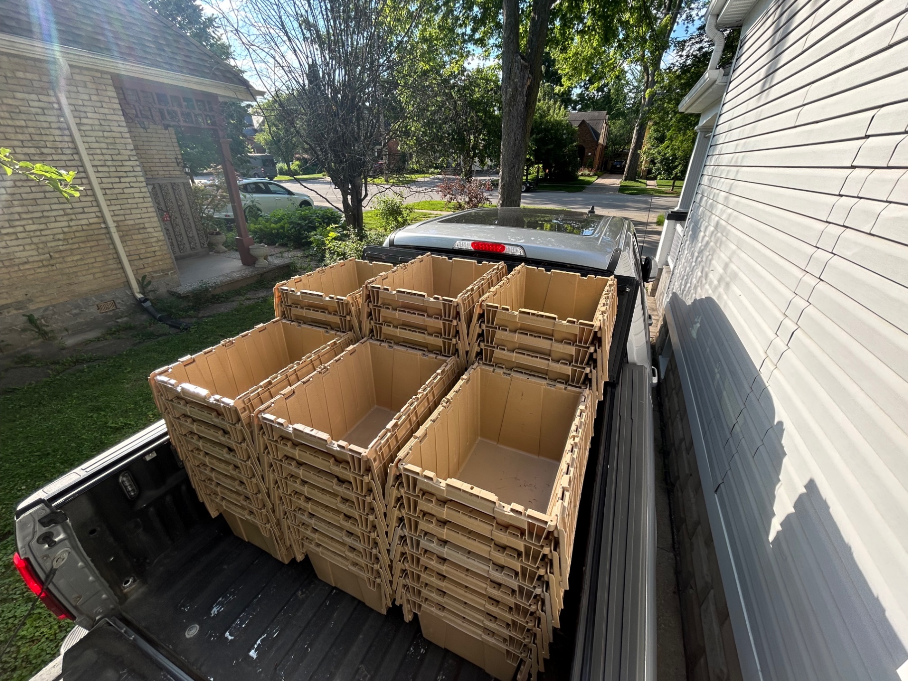 Stacks of tan moving bins loaded in a pickup truck bed